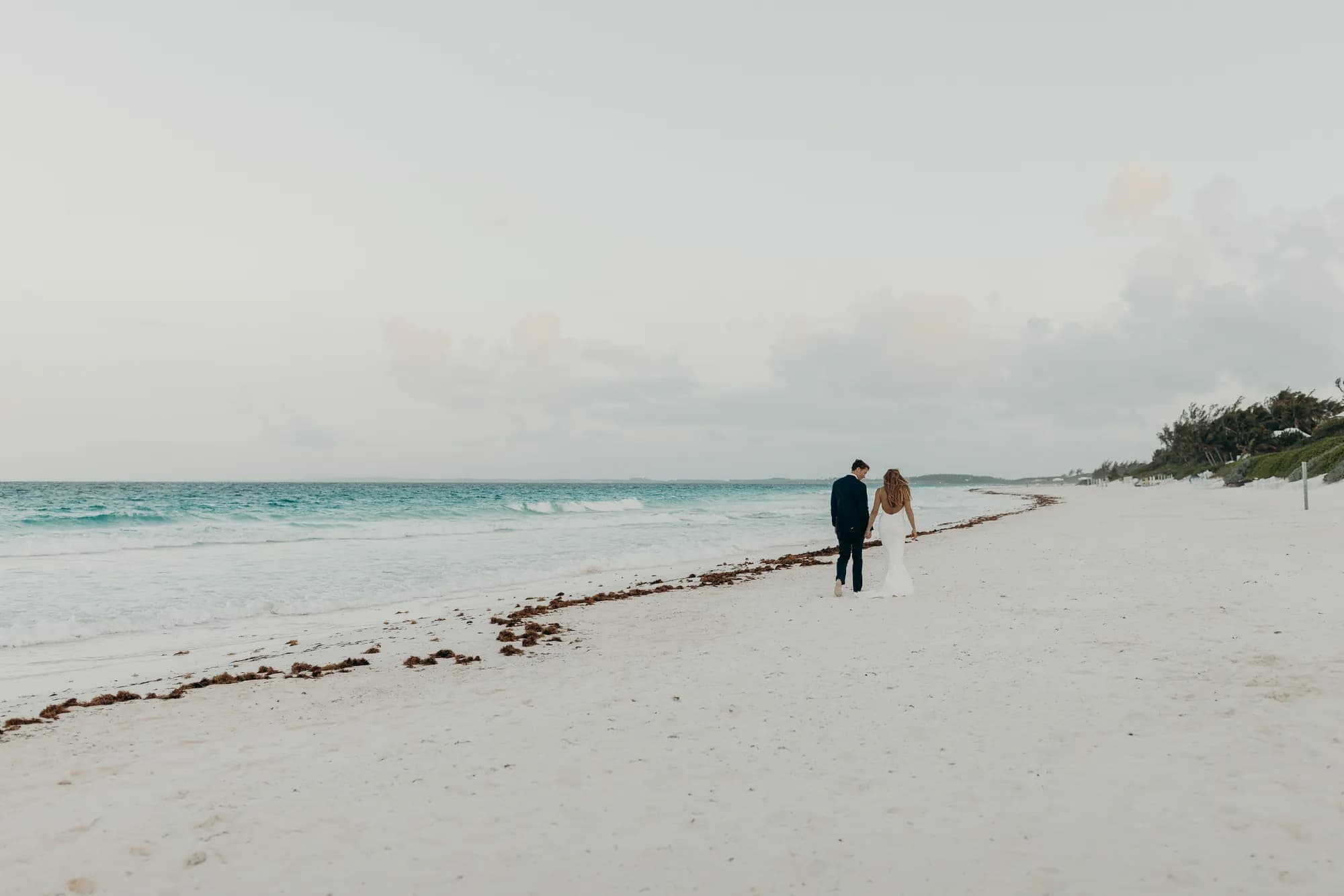 Newlyweds walking hand in hand along the shoreline