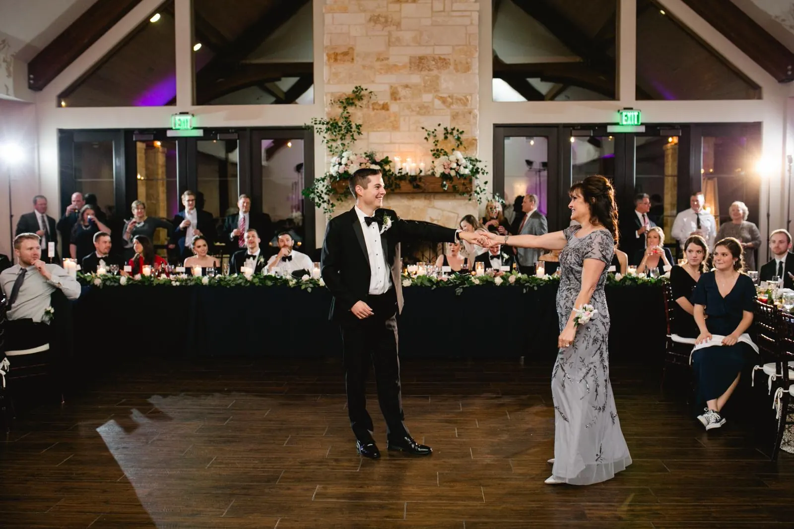 Groom and his mother dancing at the reception while guests watch
