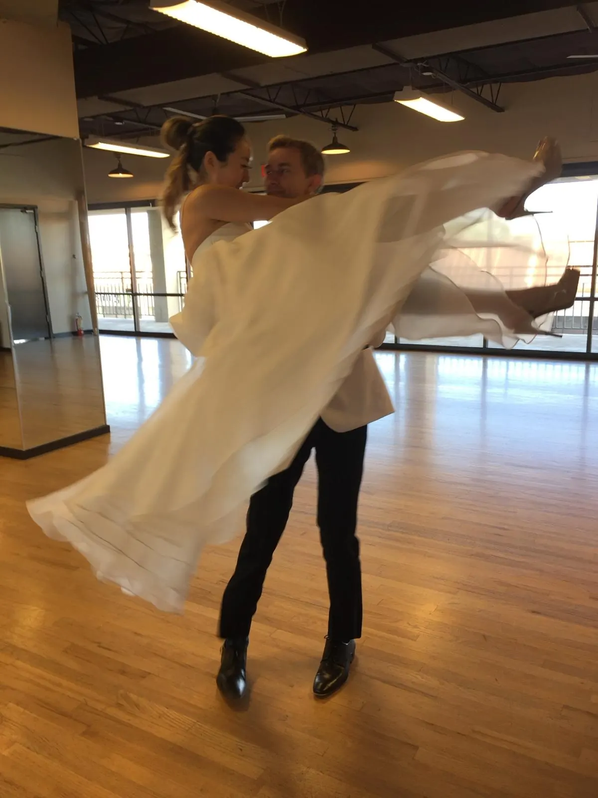 Couple practicing a dramatic lift in wedding attire at Studio 22 Dallas